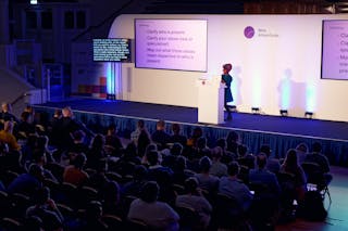 A woman stands on a stage behind a lecturn