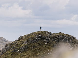 A man standing on a mountain peak, in the distance