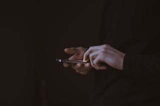 Hands using a mobile phone on a dark background