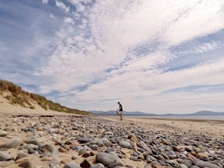 Man on a beach with a bucket and a litter picker