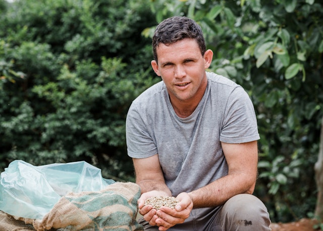 A man holding raw coffee beans in his hands