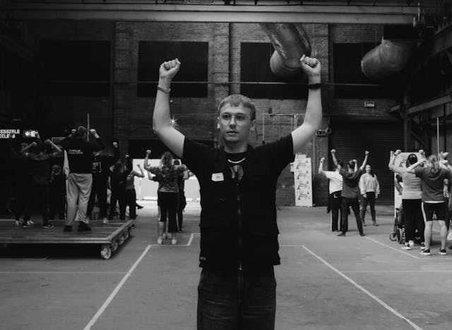 A young man holding his hands in the air in triumphant pose.