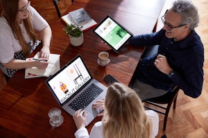 Kind team sat around a table looking at a laptop and an ipad