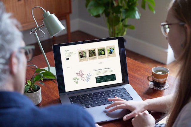 Over the shoulder view of a man and a woman looking at the Garden Organic website on a laptop