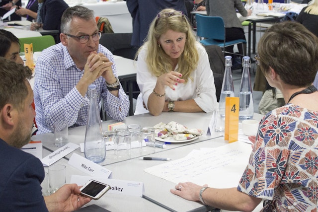 A group of people sat at a table having a discussion