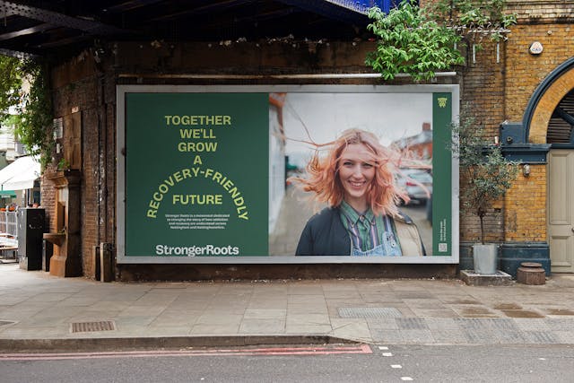Outdoor billboard showing StrongerRoots campaign with the message “Together we’ll grow a recovery-friendly future” beside a smiling young woman.