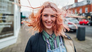 Portrait of a smiling woman with windswept hair, symbolising growth, strength and optimism in recovery.