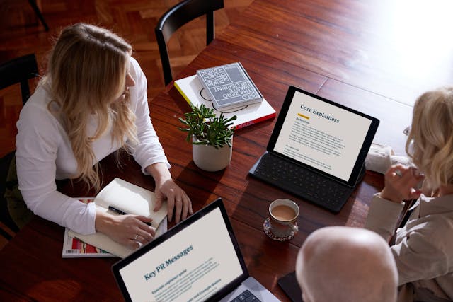 Two people from the Kind team collaborating on StrongerRoots messaging strategy at a wooden table with laptops and notes.