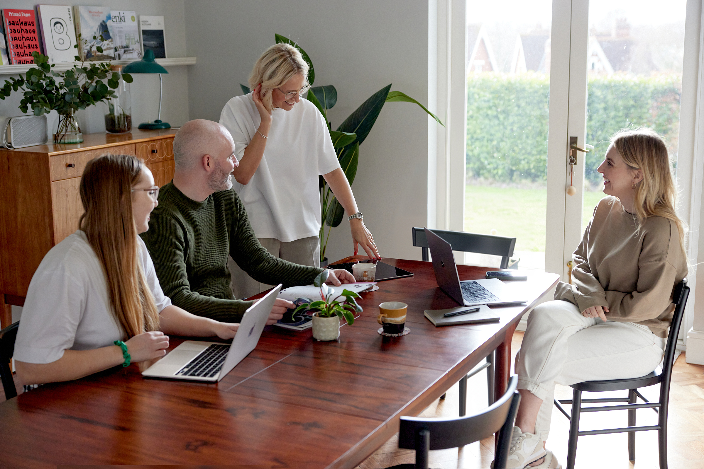 Kind team members meeting around a wooden table with laptops, collaborating on the StrongerRoots project.