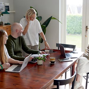 Kind team members meeting around a wooden table with laptops.