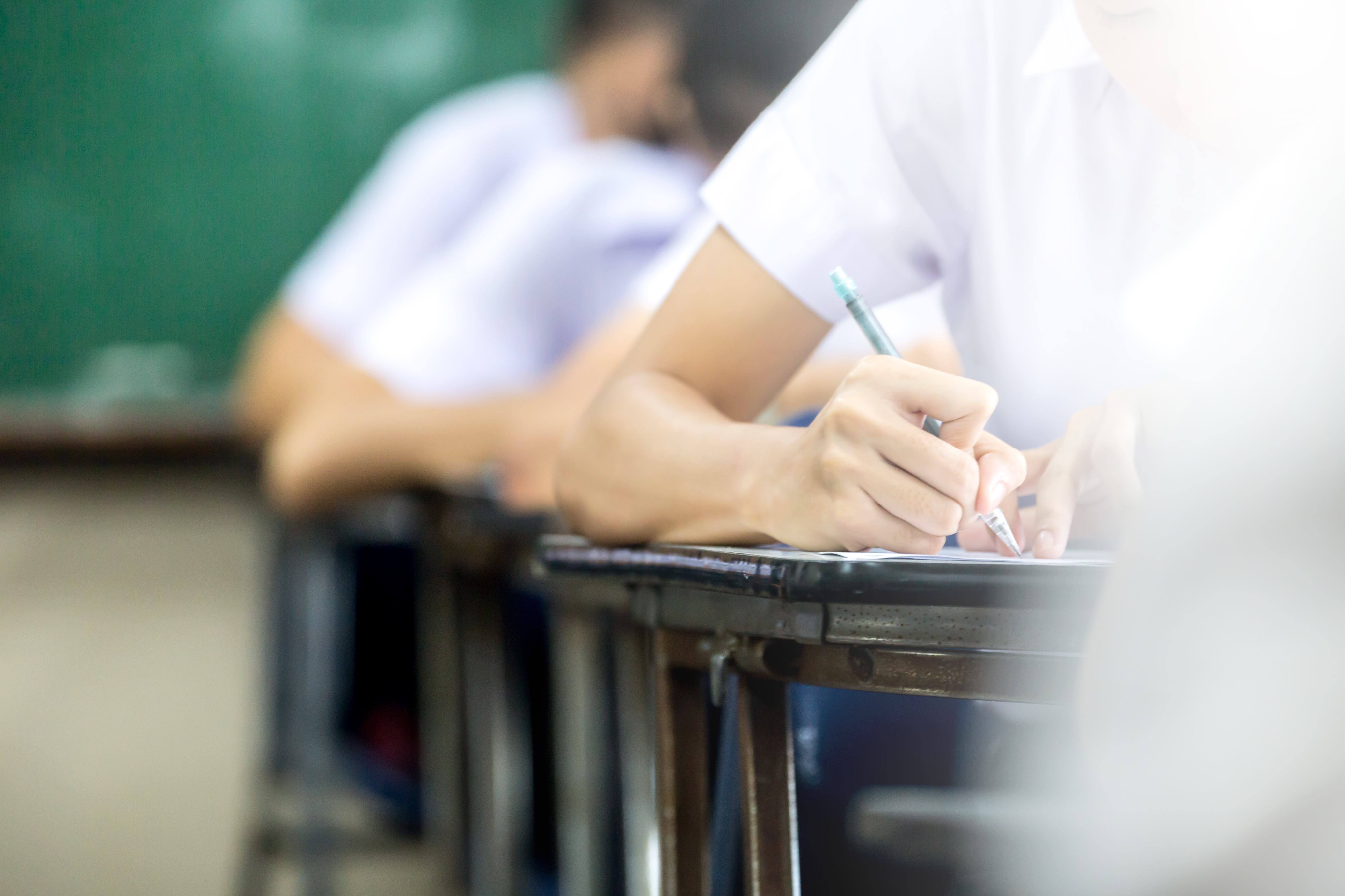 School or university student holding pencil writing on paper answer sheet