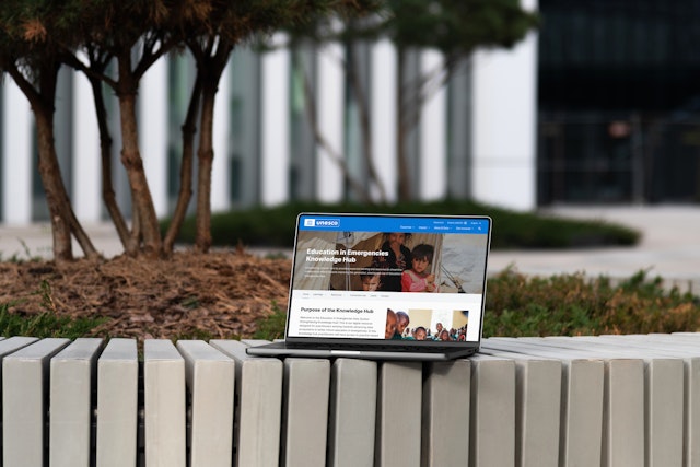 The UNESCO Education in Emergencies Knowledge Hub shown on a laptop device outside a government building