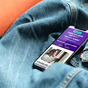 A mobile phone on a denim jacket. The mobile phone has the Papyrus website on the screen